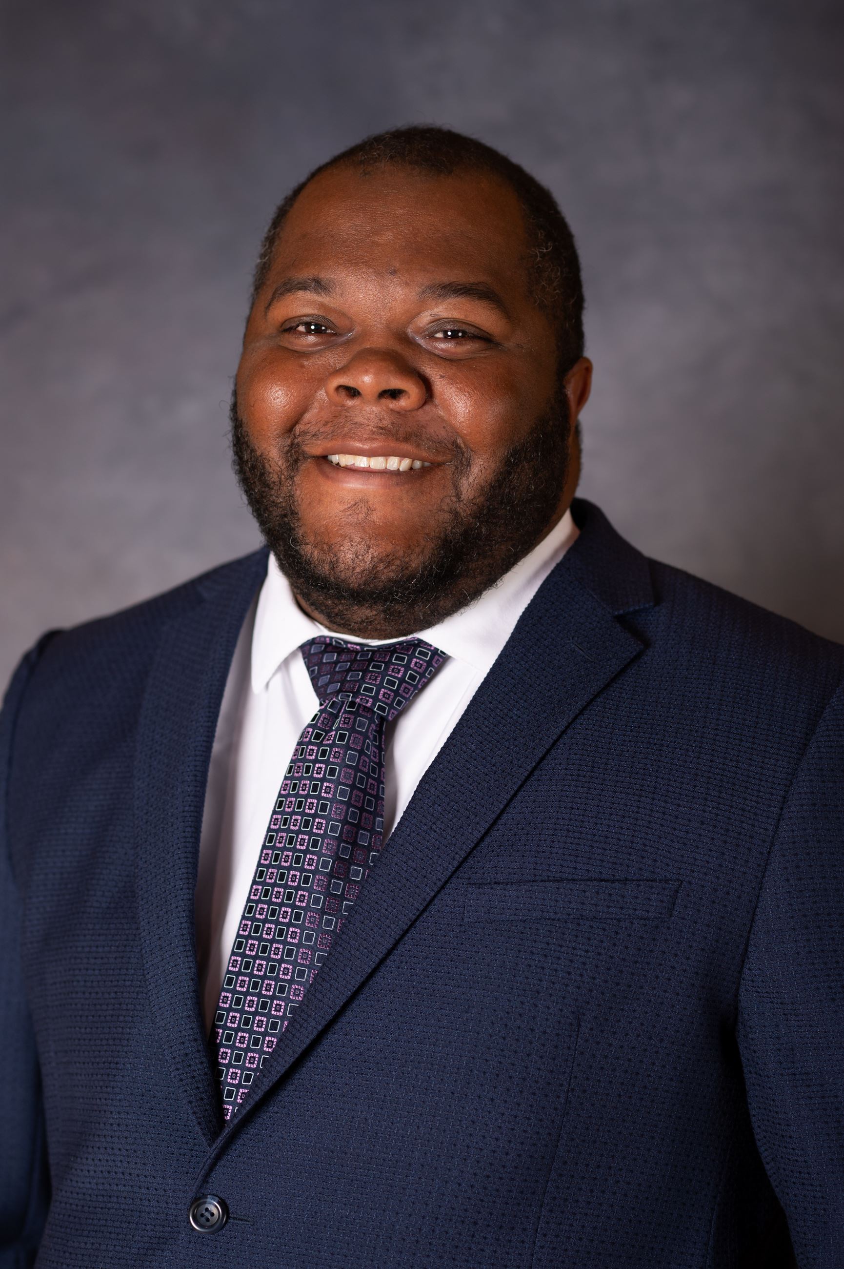 Jamel Wilcox wearing a navy suit and purple tie.